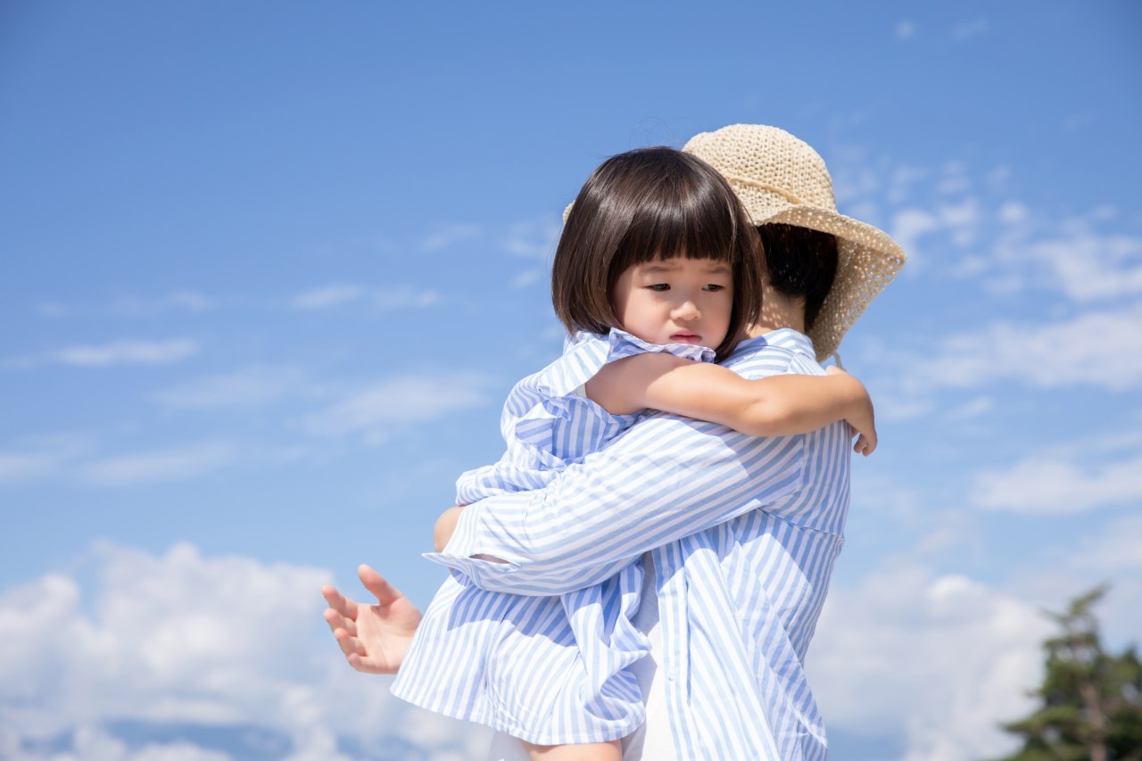 悲しそうな顔でお母さんに抱っこされる子供