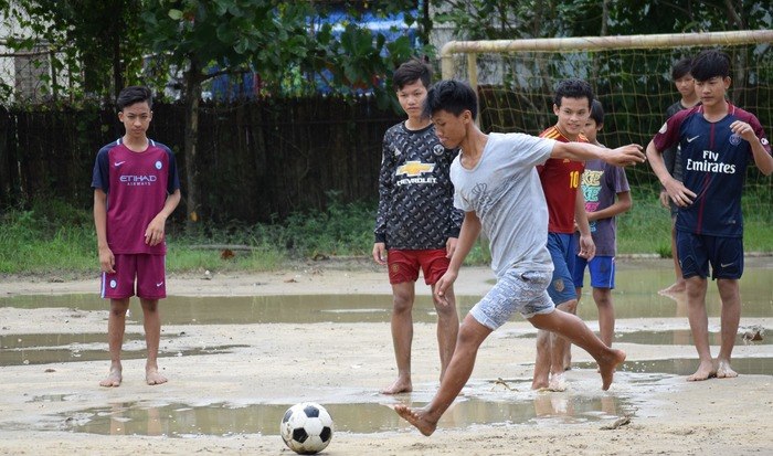水たまりだらけのグラウンドでサッカーをする子どもたち